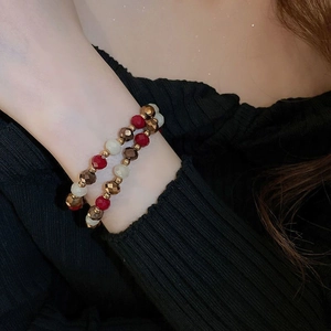 Détail du bracelet de perles avec des perles à facettes rouges, crème et bronze chic