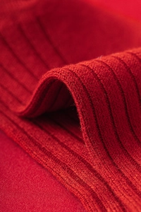 Détail macro de chaussettes en laine rouge montrant la texture côtelée et le tissu chaud