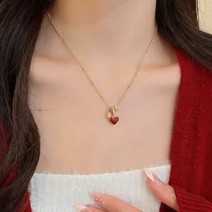 18k gold plated necklace featuring heart charm and colorful beads on red knit background