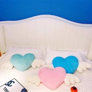 Détail de coussins en peluche en forme de cœur avec des ailes en rose, bleu et menthe