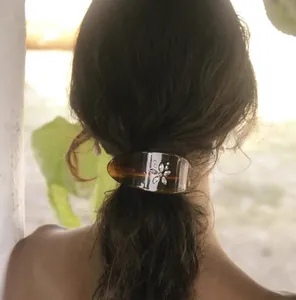 Detail of tortoise shell acetate hair clip with floral rhinestone design on low ponytail