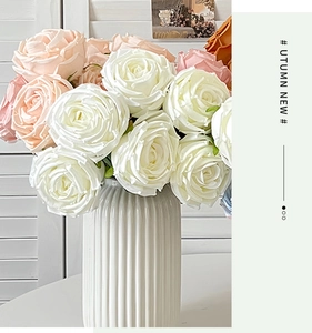 Detail of 7-head artificial silk roses in a white ribbed ceramic vase for home decor