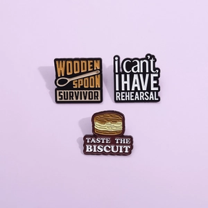 Three creative enamel pins featuring wooden spoon, rehearsal, and biscuit quote designs
