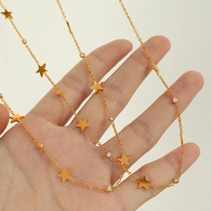 Minimalist gold star necklace with shimmering white rhinestones held by a hand