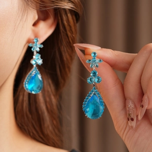 Vue détaillée de boucles d'oreilles en cristal bleu avec motifs fleurs et monture argent