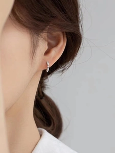 Gros plan d'une boucle d'oreille anneau argentée avec petites perles sur oreille