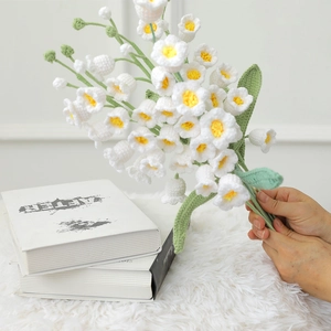 Detailed view of hand-knitted lily of the valley crochet flowers held in hand