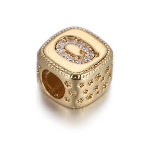 Dettaglio di una perla quadrata dorata con lettera Q in zirconia e stelle incise