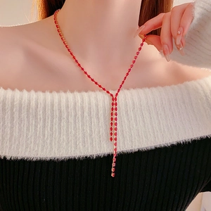 Detail of red gemstone Y-shaped necklace with dangling fringe on female model