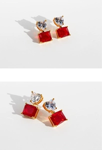Detail view of heart-shaped zircon and rectangular red gemstone stud earrings with gold plating