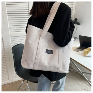 Detailed macro shot of beige canvas tote bag showing high-quality linen texture and label