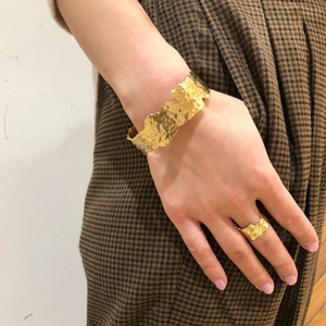 Bracelet manchette et bague dorés avec texture rocheuse irrégulière portés par modèle