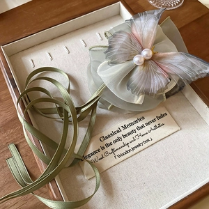 Elegant organza butterfly hair clip with pearls resting on a vintage wooden box