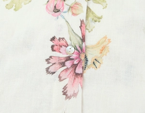 Detailaufnahme der Leinenbluse mit Blumendruck und runden Knöpfen im französischen Stil