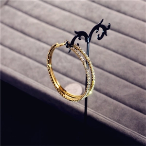 Detailed view of oversized gold and silver hoop earrings with sparkling crystal rhinestones