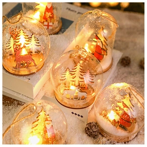 Detail of LED glowing Christmas glass ball with Santa and reindeer on wood base