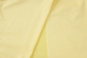 Gros plan détaillé d'un tissu en maille jaune clair montrant texture et drapé fluide