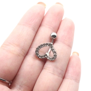 Détail d'un piercing de nombril en argent avec cœur et strass sur les doigts