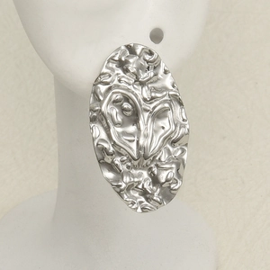 Macro detail of irregular lava texture on silver oval 304 stainless steel earrings