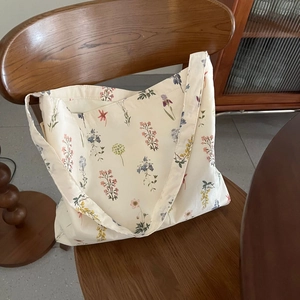 Close-up of beige canvas tote bag featuring delicate floral prints on a wooden chair