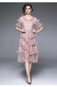Détail d'une robe en dentelle rose avec volants superposés et broderie sur le décolleté en V