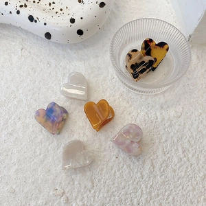 Close-up of heart-shaped acetate hair claws in various marble and tortoiseshell patterns