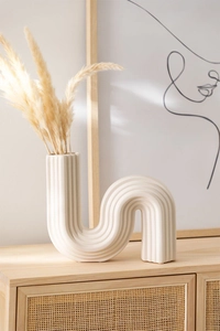 Detalle del jarrón de cerámica minimalista en forma de U con textura de rayas verticales