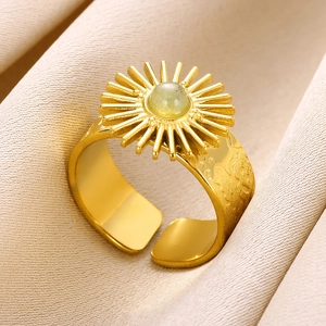 Macro detail of sunburst gold titanium steel ring featuring a round green stone inlay