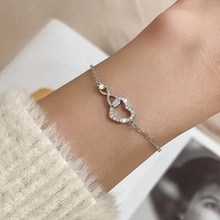 Macro detail of silver heart infinity chain bracelet with pavé white zircon stones