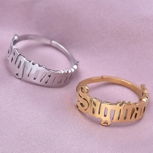 Macro detail of gold and silver Sagittarius rings with gothic cutout lettering on satin