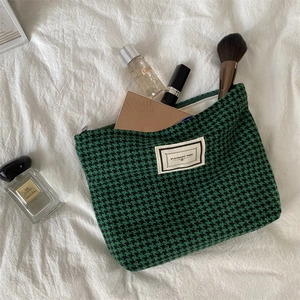 Detailed close-up of green houndstooth cosmetic bag with luxury beauty items