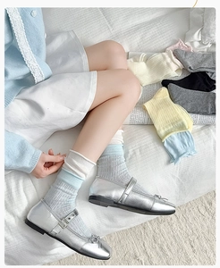 Close-up of pastel ruffled mid-calf socks with Mary Jane shoes on a cozy bed background