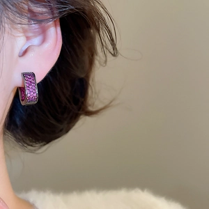 Close-up of a model wearing purple zircon pavé hoop earrings in black gunmetal finish