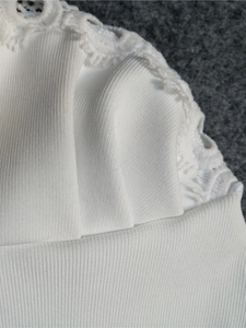 Détail du tissu en maille côtelée blanche avec dentelle délicate et design plissé