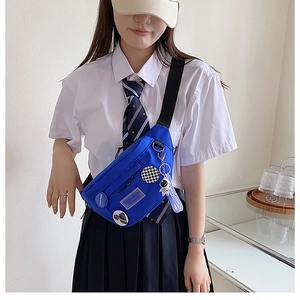 Detail of blue canvas chest bag with astronaut pendant and badges for school style