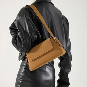 Brown faux suede underarm bag with adjustable strap worn by model on black leather jacket