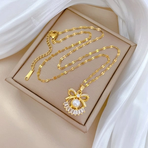 Macro shot of gold stainless steel necklace with crystal bow pendant and white pearl