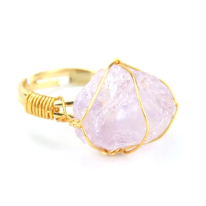 Close-up of handmade wire-wrapped raw purple amethyst stone on an adjustable gold ring