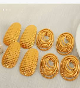Close-up of golden checkered embossed and spiral oval titanium steel earrings