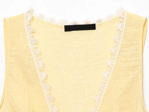 Detailed close-up of yellow knit top featuring delicate white floral lace trim on neckline