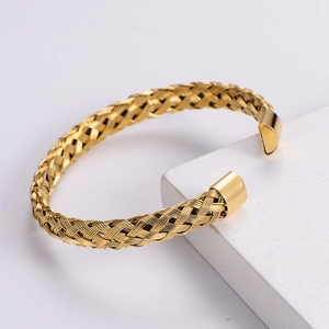 Detail of gold woven stainless steel wire bracelet with polished cylinder ends