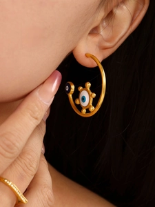 Close-up of gold enamel evil eye hoop earrings on model featuring 18K gold plated texture
