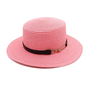 Detail of pink straw boater hat with black ribbon and gold pin buckle accent