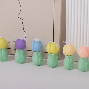 Fila de velas aromáticas con forma de tulipán en tonos púrpura, azul y amarillo