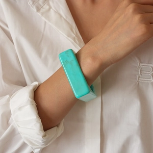 Close-up of a mint green marble texture acrylic geometric wide bangle on model wrist