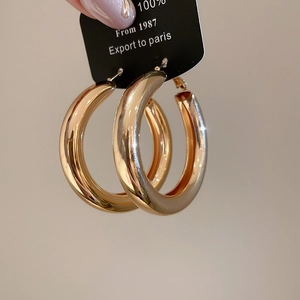 Detailed view of large polished gold hoop earrings presented on a classic black display card