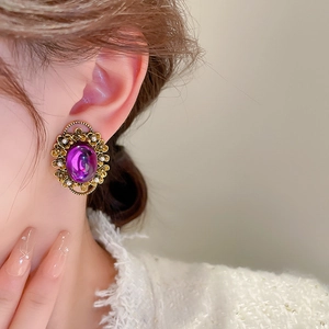 Detailed close-up of a vintage purple oval pearl ear clip with gold floral engraving