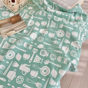 Detail of mint green linen tablecloth with white kitchen illustrations and soft drapes