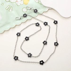 Detail of silver irregular metal chain strap with black floral charms and spring clasps