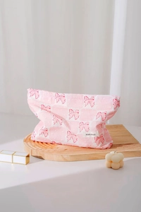 Dettaglio trousse in tessuto rosa con motivo a fiocchi rossi e trama a pois in rilievo